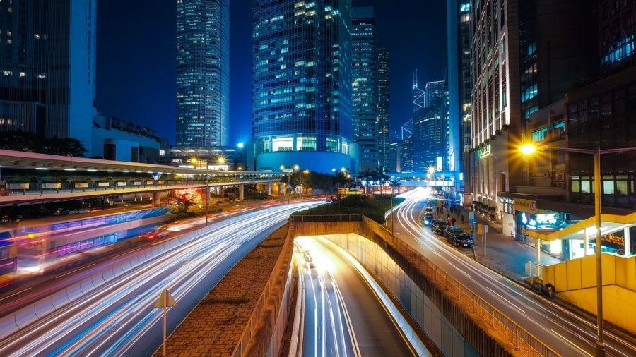 Long exposure photography capturing light trails on a busy street at night.